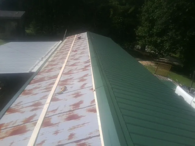 Old rusted panels beside newly installed green metal roofing — Wind Damage Roof Repair by Roofing Brothers in Carthage